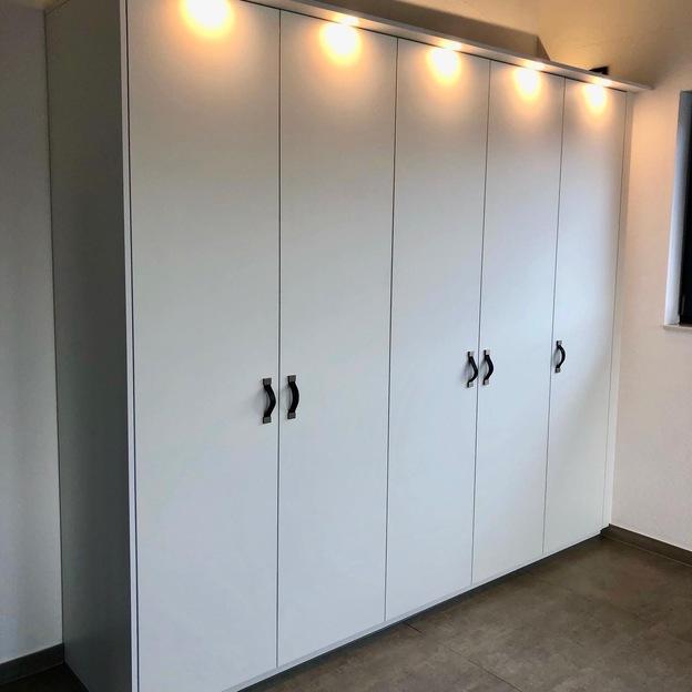 Schrank nach Maß von Tischlerei Krogull Maßgefertigter Schrank mit eleganten Griffen und integrierter Beleuchtung, perfekt für moderne Wohnräume.