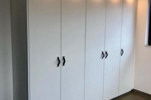 Schrank nach Maß von Tischlerei Krogull Maßgefertigter Schrank mit eleganten Griffen und integrierter Beleuchtung, perfekt für moderne Wohnräume.
