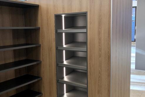Raumtrennwand mit Regalsystem von Tischlerei Krogull Funktionale Raumtrennwand in Holzoptik mit integriertem, beleuchtetem Regalsystem für eine stilvolle Aufbewahrungslösung.