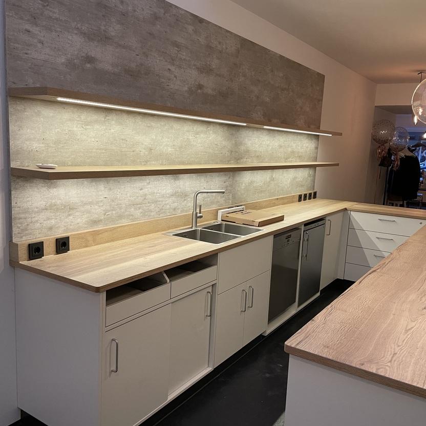 Maßgefertigte Küchenzeile mit Holzarbeitsplatten von Tischlerei Krogull Stilvolle Küchenzeile mit Holzarbeitsplatten, offenen Regalen und integrierter Beleuchtung in modernem Design.