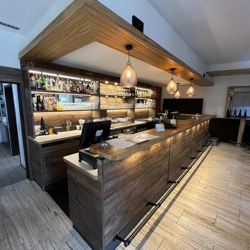 Maßgefertigte Bar mit Beleuchtung von Tischlerei Krogull Elegante Bar mit Holzverkleidung, integriertem Regalsystem und stimmungsvoller Beleuchtung für eine einladende Atmosphäre.