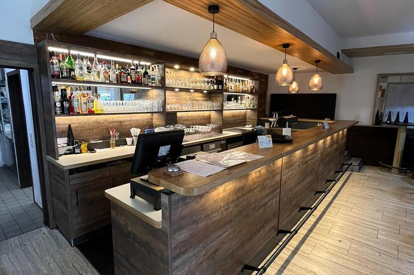 Maßgefertigte Bar mit Beleuchtung von Tischlerei Krogull Elegante Bar mit Holzverkleidung, integriertem Regalsystem und stimmungsvoller Beleuchtung für eine einladende Atmosphäre.