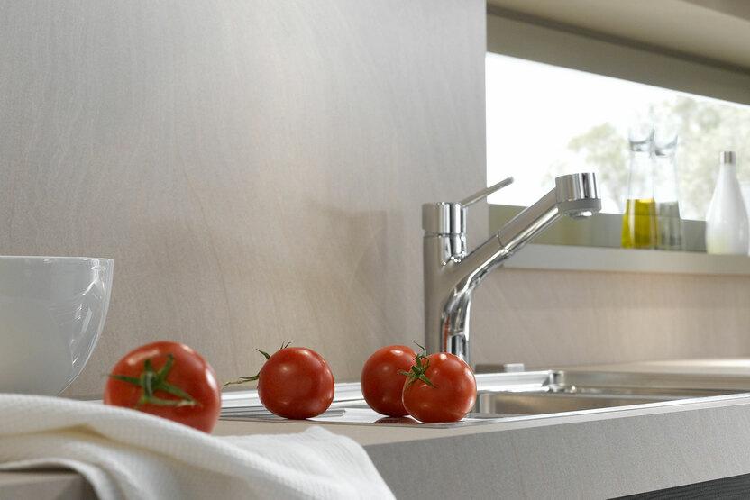 Detailaufnahme mit grauen Hängeschränken und Unterbodenbeleuchtung und einer hellen Arbeitsplatte