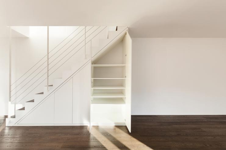 Nischenlösung für Einbauschrank unter Treppe Geräumiger Einbauschrank unter weißer Treppe mit Schubläden und Türen und offener Regalgestaltung an dunklem Parkett